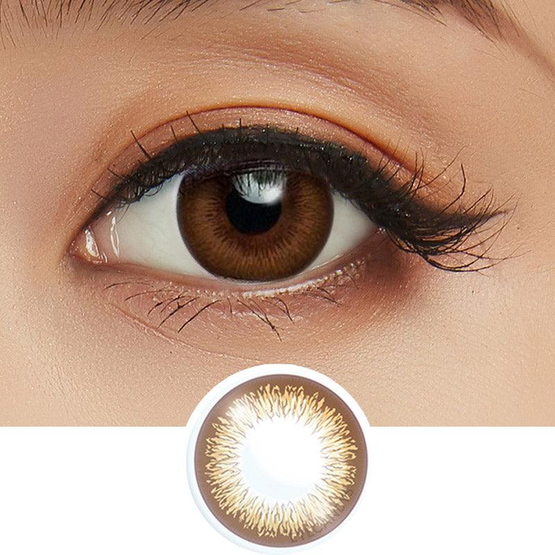 Close-up shot of model's eye adorned with Acuvue 1-Day Define Radiant Brown color contact lens dailies, complemented by clean eye makeup, showing the brightening effect of the circle lenses on dark brown eyes, above a cutout of the colour contact lens design with radial spiked pattern
